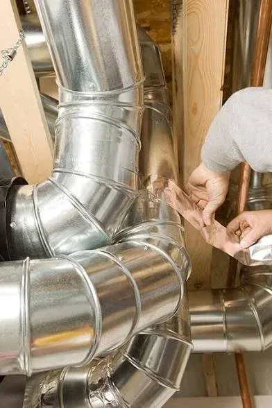 Technician sealing a metal duct joint